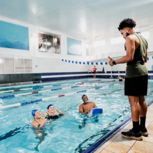 instructor talking with students at swimming pool